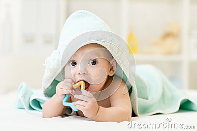 Baby with teether in mouth under bathing towel at nursery Stock Photo