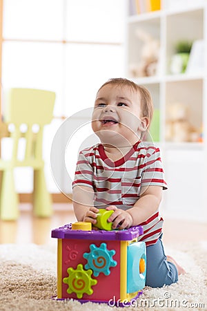 Baby toddler playing indoors with sorter toy sitting on soft carpet Stock Photo