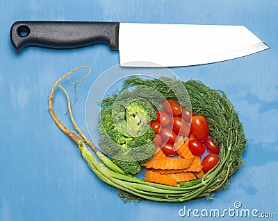 baby tomatoes. carrot. broccoli. knife. on wood blue sky background. space Stock Photo