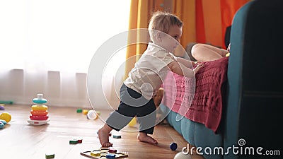 baby tries to get up, takes his a first steps, leans on the sofa. happy family kid dream concept. baby takes his first Stock Photo