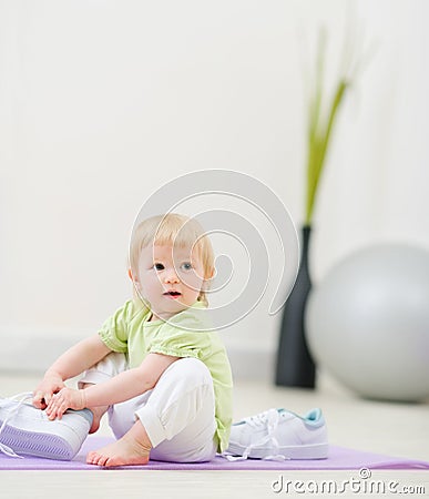 Baby trying to wear big sneakers Stock Photo