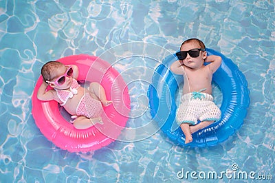 Baby Twin Boy and Girl Floating on Swim Rings Stock Photo