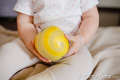 Baby two hands hold yellow apple. Toddler`s hands and fresh fruit front view. Flat lay diet and healthy food concept. Stock Photo