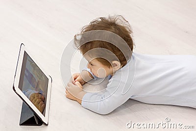 Baby watching cartoons on her tablet computer in the background of the toys he child does not want to play Stock Photo