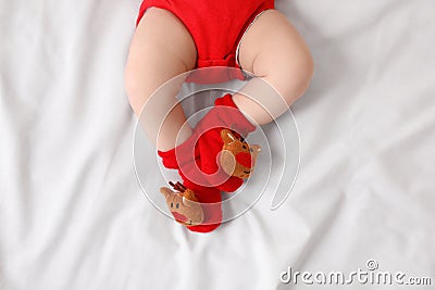 Baby wearing festive Christmas socks on white bedsheet, top view Stock Photo