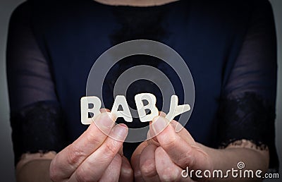 BABY. Word from white letters of wooden alphabet in woman& x27;s hand Stock Photo