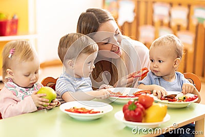 Babysitter feeding nursery babies. Toddlers eat healthy food in daycare Stock Photo