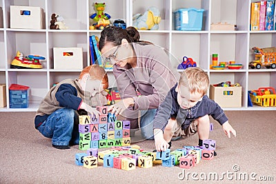 Babysitter playing kids block game with children Stock Photo