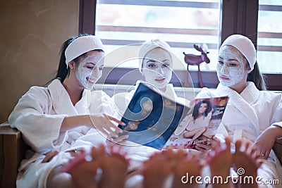 Bachelorette party in spa, girls with face mask reading magazine Stock Photo