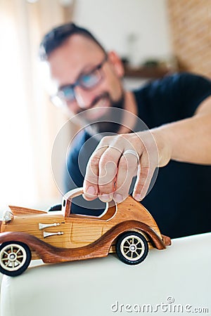 Back in childhood, man playing with wooden toy car Stock Photo