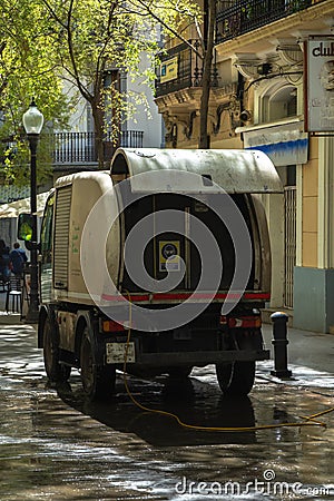 Back of a cleaning truck from the municipal service brigade of Barcelona, cleaning a pedestrian street with the hose watering the Stock Photo