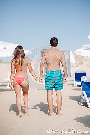 Back couple walking on the beach. On the back of a man and on the woman`s buttocks is handprint of sand Stock Photo