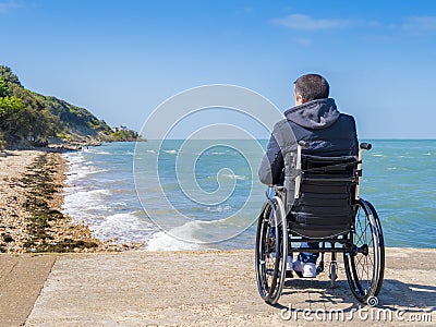 Back of disabled man in wheelchair at beach Stock Photo