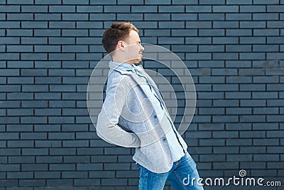 Back or kidney pain profile side view portrait of sick or tired handsome young blonde man in casual style standing and holding his Stock Photo