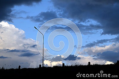 Back light Lamp post meadow and Dark blue stormy cloudy sky in evening Stock Photo