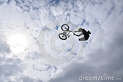 Silhouette of a young man freestyle stunt cyclist flying in the sky Stock Photo