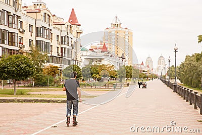 The back of Roller skater rides by sidewalk in city Editorial Stock Photo