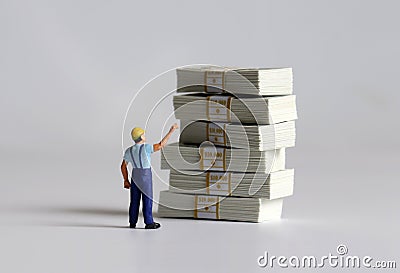 The back of a miniature man pointing at a bundle of bills and it. Stock Photo