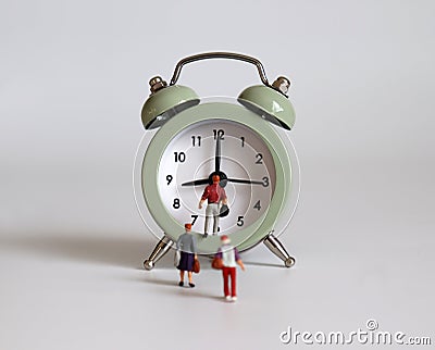 The back of the miniature people walking into the alarm clock. Stock Photo