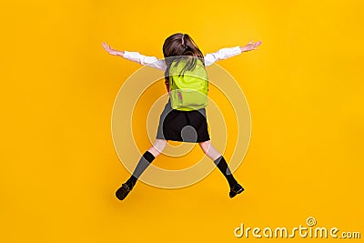 Back rear spine side view photo of small schoolgirl jump up wear backpacki solated on yellow color background Stock Photo