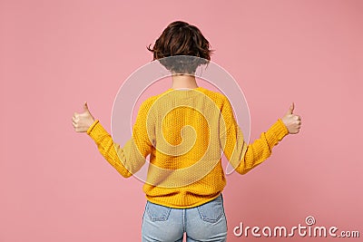 Back rear view of young brunette woman girl in yellow sweater posing isolated on pink wall background studio portrait Stock Photo