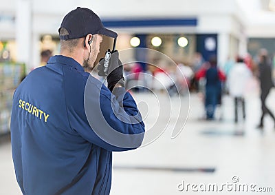 Back of security guard with walkie talkie against blurry shopping centre Stock Photo