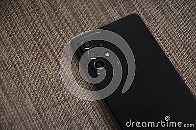 Back side of black color mobile phone smartphone over textured background Stock Photo