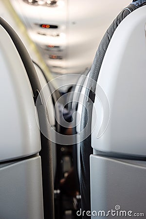 Back side of generic airplane seats next to each other shallow depth of field view forward to passengers Stock Photo
