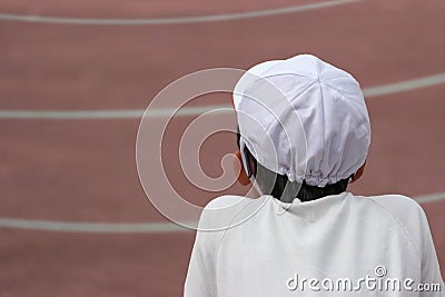 Back side of a Japanese primary student boy who sitting near running race and cheering friends in sports day games at public park Editorial Stock Photo