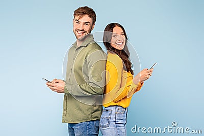 Back-to-back couple with phones, smiling and engaged in digital Stock Photo