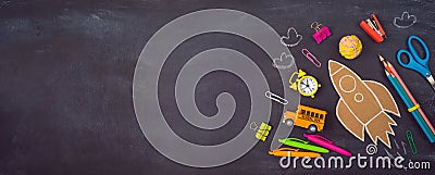 Back to school background with cardboard rocket and school supplies over chalkboard. Top view from above Stock Photo