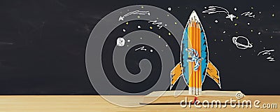 Back to school banner. rocket sketch and pencils over open book in front of classroom blackboard. Stock Photo
