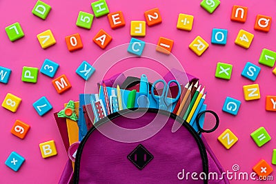 Back to school concept. Backpack with school supplies and alphabets and numbers blocks on pink background. Top view. Copy space Stock Photo