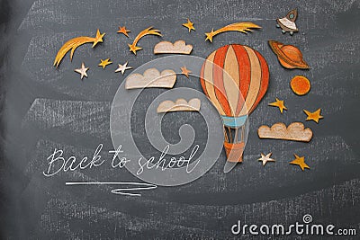 Back to school concept. Hot air balloon, space elements shapes cut from paper and painted over classroom blackboard background. Stock Photo