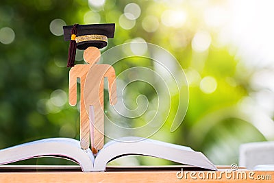 Back to School Concept, Man Sign wood with Graduation cap on open textbook with light green background. Graduate or Education Stock Photo
