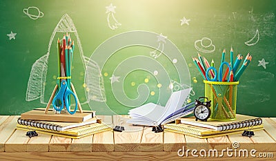 Back to school concept with rocket sketch, pencils and notebook on wooden table over chalkboard background Stock Photo