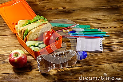 Back to school concept. School supplies, bottle of water, apple and lunch box with sandwiches and fresh vegetables Stock Photo