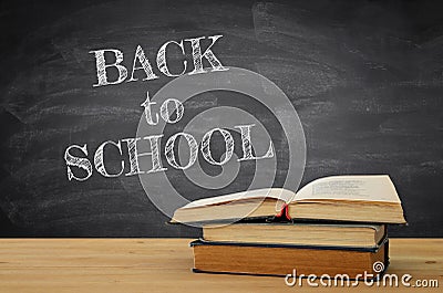 back to school concept. stack of books over wooden desk in front of blackboard. Stock Photo