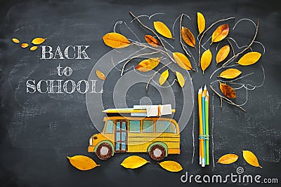 Back to school concept. Top view image of school bus and pencils next to tree sketch with autumn dry leaves over classroom blackbo Stock Photo