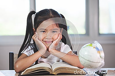 Cute asian child girl with a book smiling in the classroom Stock Photo