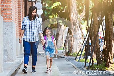 Cute asian pupil girl with backpack holding her mother hand and going to school Stock Photo