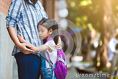 Cute asian pupil girl with backpack hugging her mother with sadness before go to classroom in the school Stock Photo