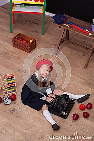 Back to school! The girl in the beret sits with a typewriter and learns in class. On the blackboard in the Ukrainian language is w Stock Photo