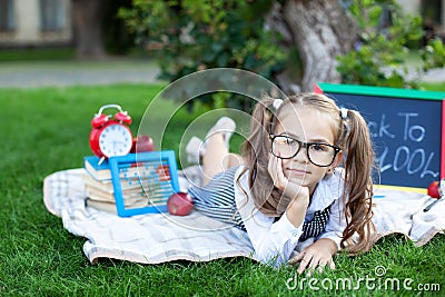 Back to school. The kid is ready for school. smart child little girl in glasses with school supplies a school board, books, a magn Stock Photo