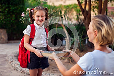 Back to school. Mother giving book to her child before going to school Stock Photo