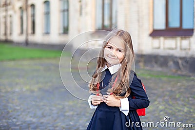 Back to school. Pupil of primary school. Girl with backpack near building outdoors. Beginning of lessons. First day of fall. Happy Stock Photo