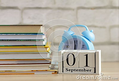 Back to school, September 1 on the calendar. Alarm clock and a stack of textbooks on the table Stock Photo