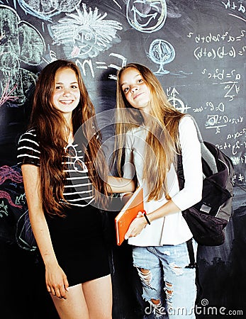 Back to school after summer vacations, two teen real girls in classroom with blackboard painted together, lifestyle Stock Photo