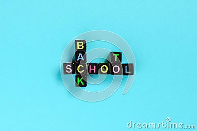 Back to school text from colorful letters on black cubes laid out in form of crossword puzzle, blue background. Concept education Stock Photo