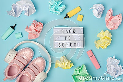 Back to school text on lightbox. Headphones, pink shoes, colored crumpled paper balls, marker on blue background Stock Photo